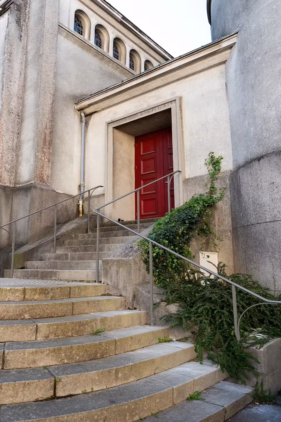 Mains courantes sur-mesure installées par Coyac sur les marches d'accès à la porte latérale rouge de l'église Notre-Dame de Toute Joie à Nantes