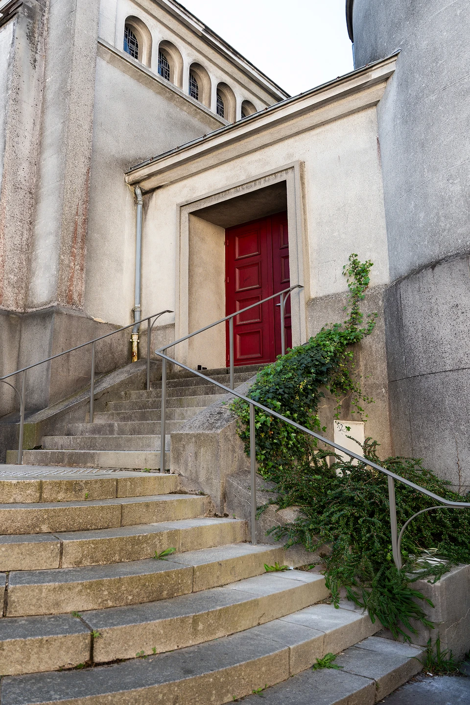 Mains courantes sur-mesure installées par Coyac sur les marches d'accès à la porte latérale rouge de l'église Notre-Dame de Toute Joie à Nantes