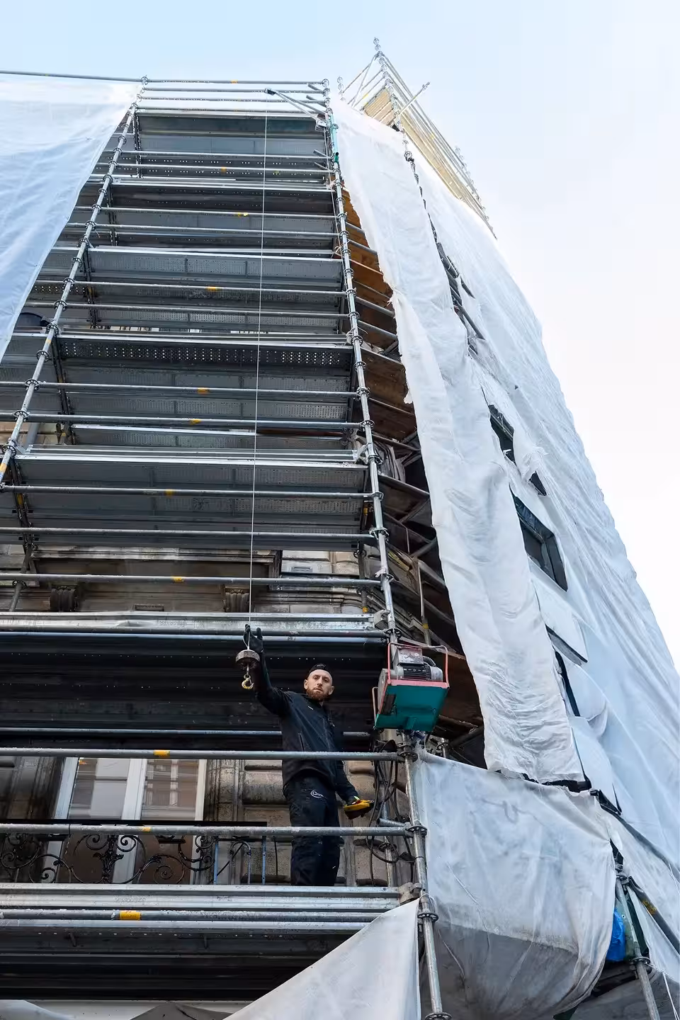 Compagnon ferronnier de Coyac manœuvrant un treuil sur échafaudage pour la restauration des garde-corps d'un immeuble de caractère quartier Graslin à Nantes