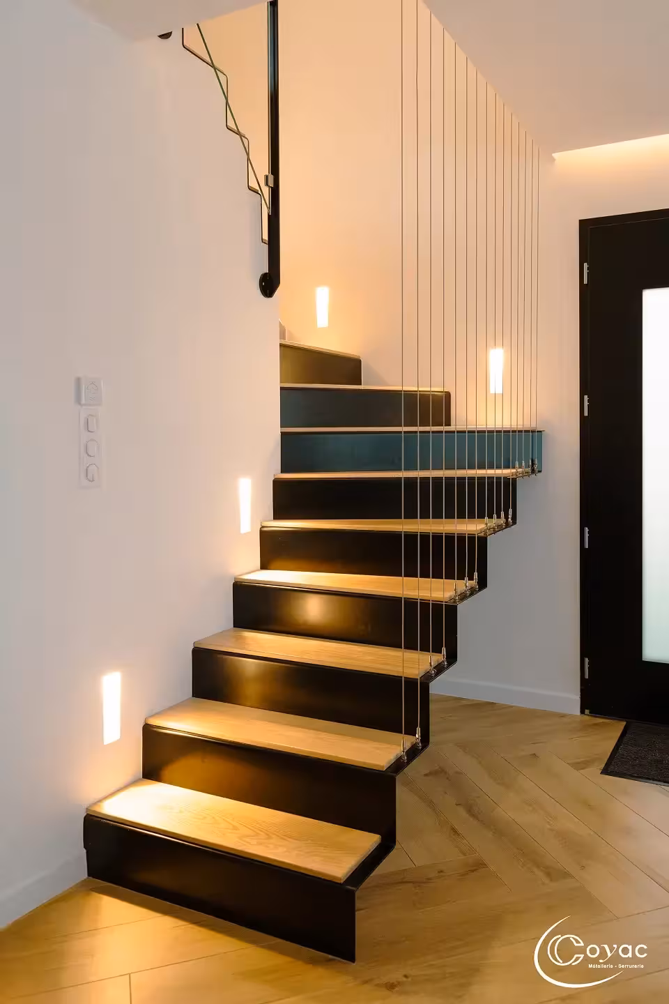 Escalier sur-mesure métal et bois au design aérien à Savenay, avec marches pliées en chêne, garde-corps à câbles inox et éclairage d'ambiance, fabriqué par Coyac