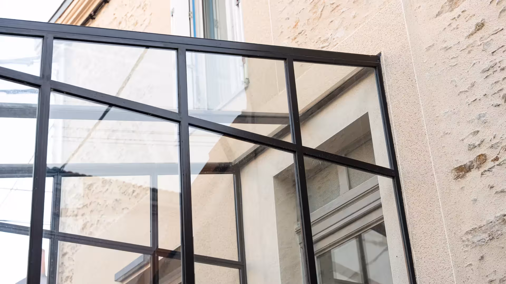 Détail des profilés métalliques noirs d'une verrière sur-mesure en raccord avec une façade en pierre à Trentemoult