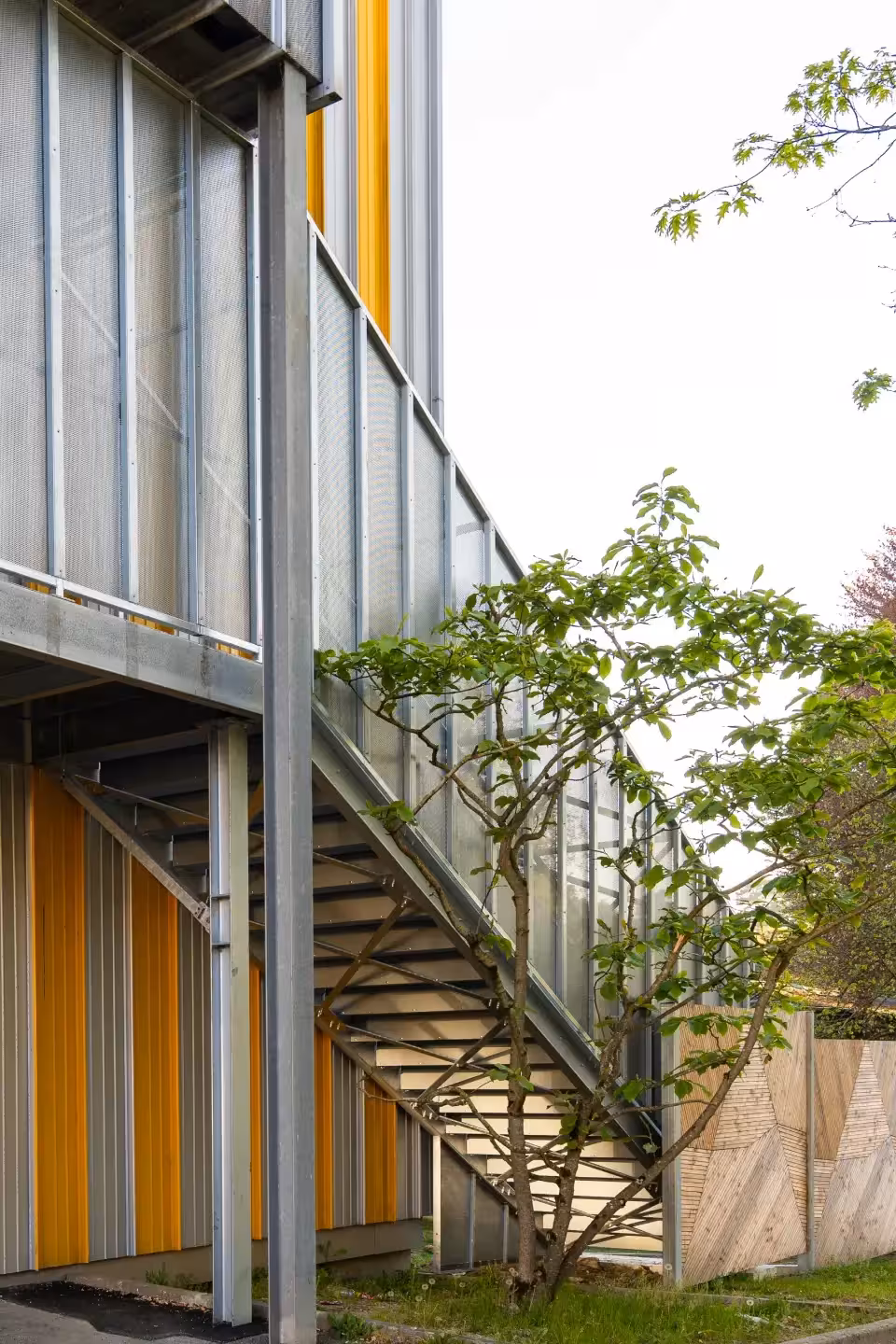Vue latérale d'une cage d'escalier métallique habillée de tôle perforée au CHU Saint-Jacques de Nantes, fabriquée et posée par Coyac