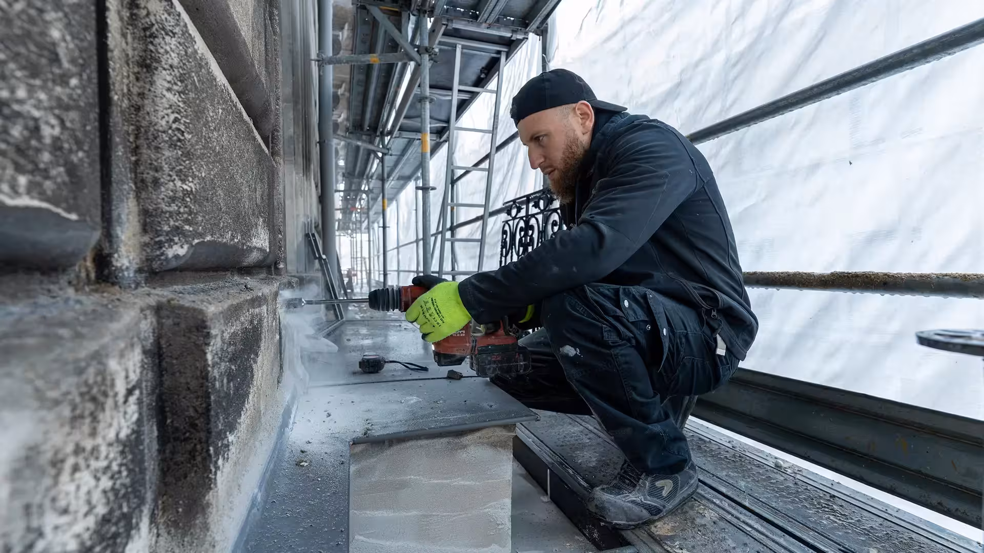 Compagnon Coyac réalisant un perçage dans la pierre pour le scellement d'un garde-corps restauré sur la façade d'un immeuble quartier Graslin à Nantes
