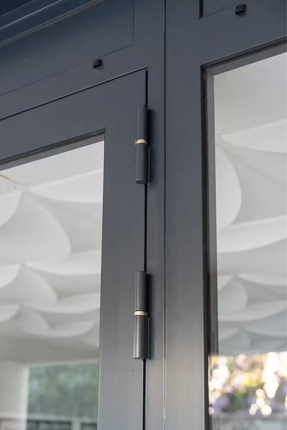 Détail des charnières et de la menuiserie en acier d'une porte de hall d'immeuble à Nantes, finitions soignées par Coyac