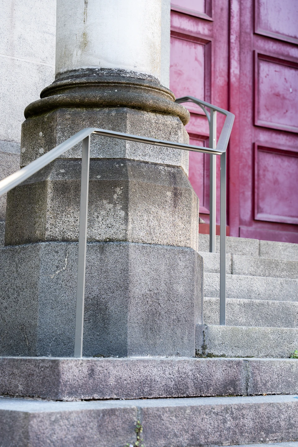 Mains courantes sur-mesure en acier laqué clair posées au pied d'une colonne en granit, devant la porte principale de l'église Notre-Dame de Toute Joie à Nantes