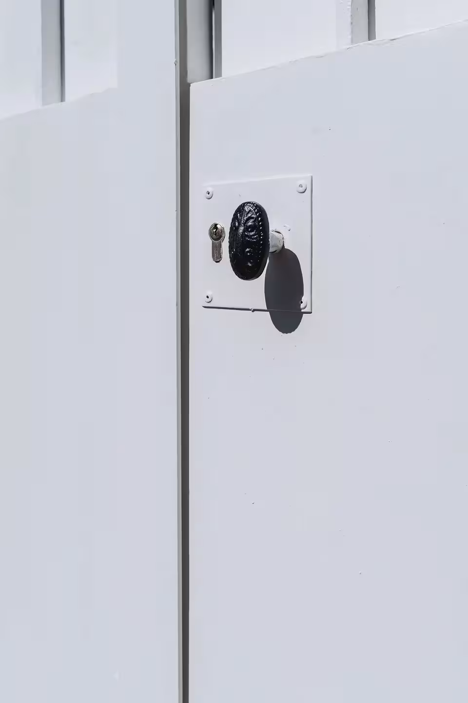 Détail de la nouvelle serrure en applique à cylindre sécurisé et du bouton de tirage en fonte sur un portail en fer forgé rénové par Coyac à Nantes