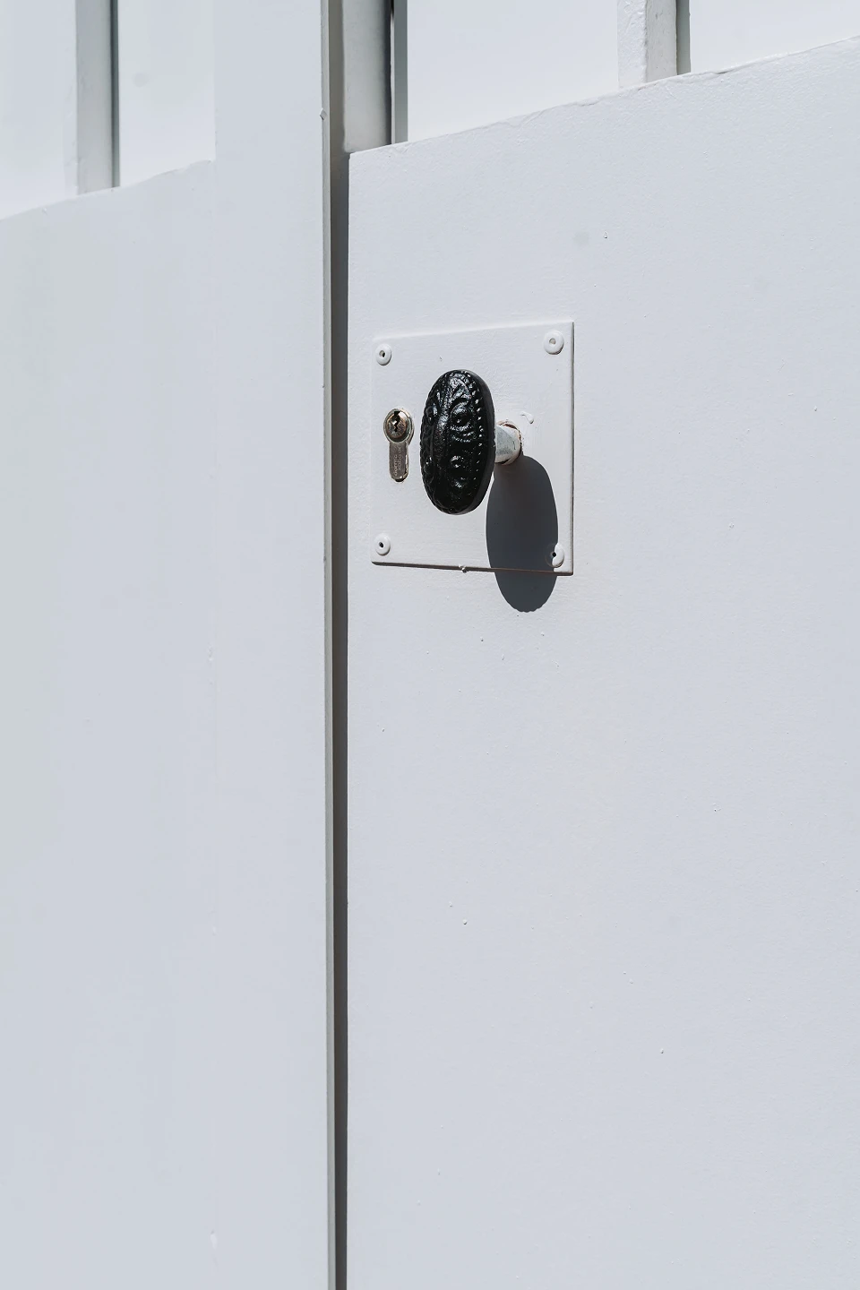 Détail de la nouvelle serrure en applique à cylindre sécurisé et du bouton de tirage en fonte sur un portail en fer forgé rénové par Coyac à Nantes