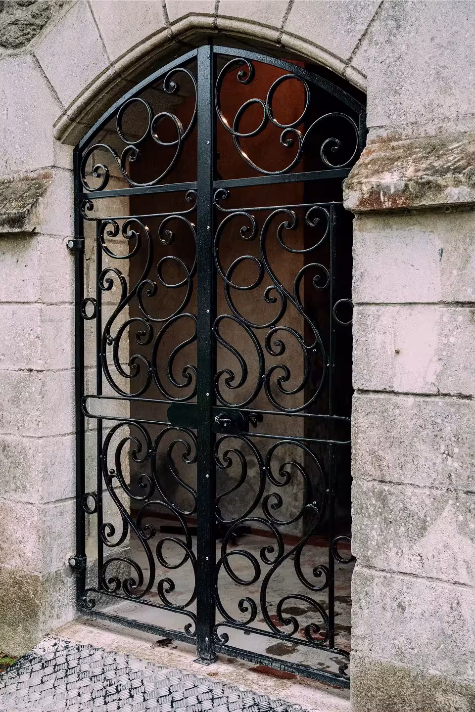 Grille en fer forgé en arc, intégrée à une ouverture en pierre, fabriquée à la forge par Coyac près de la Beaujoire à Nantes