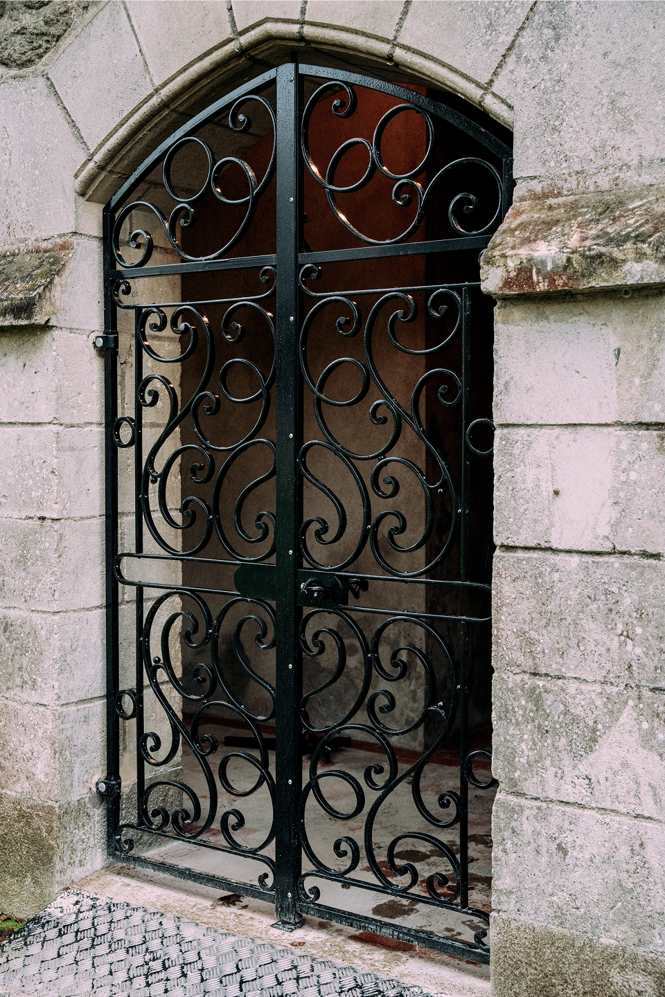 Grille en fer forgé en arc, intégrée à une ouverture en pierre, fabriquée à la forge par Coyac près de la Beaujoire à Nantes