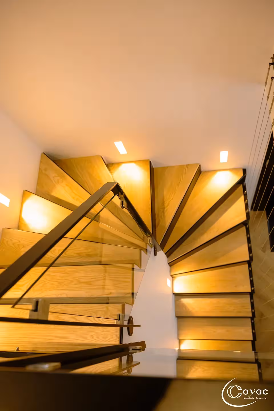 Vue en plongée sur les marches pliées en éventail d'un escalier sur-mesure métal et bois à Savenay, illustrant le tracé technique réalisé par Coyac