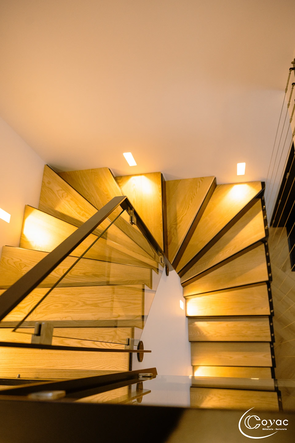 Vue en plongée sur les marches pliées en éventail d'un escalier sur-mesure métal et bois à Savenay, illustrant le tracé technique réalisé par Coyac