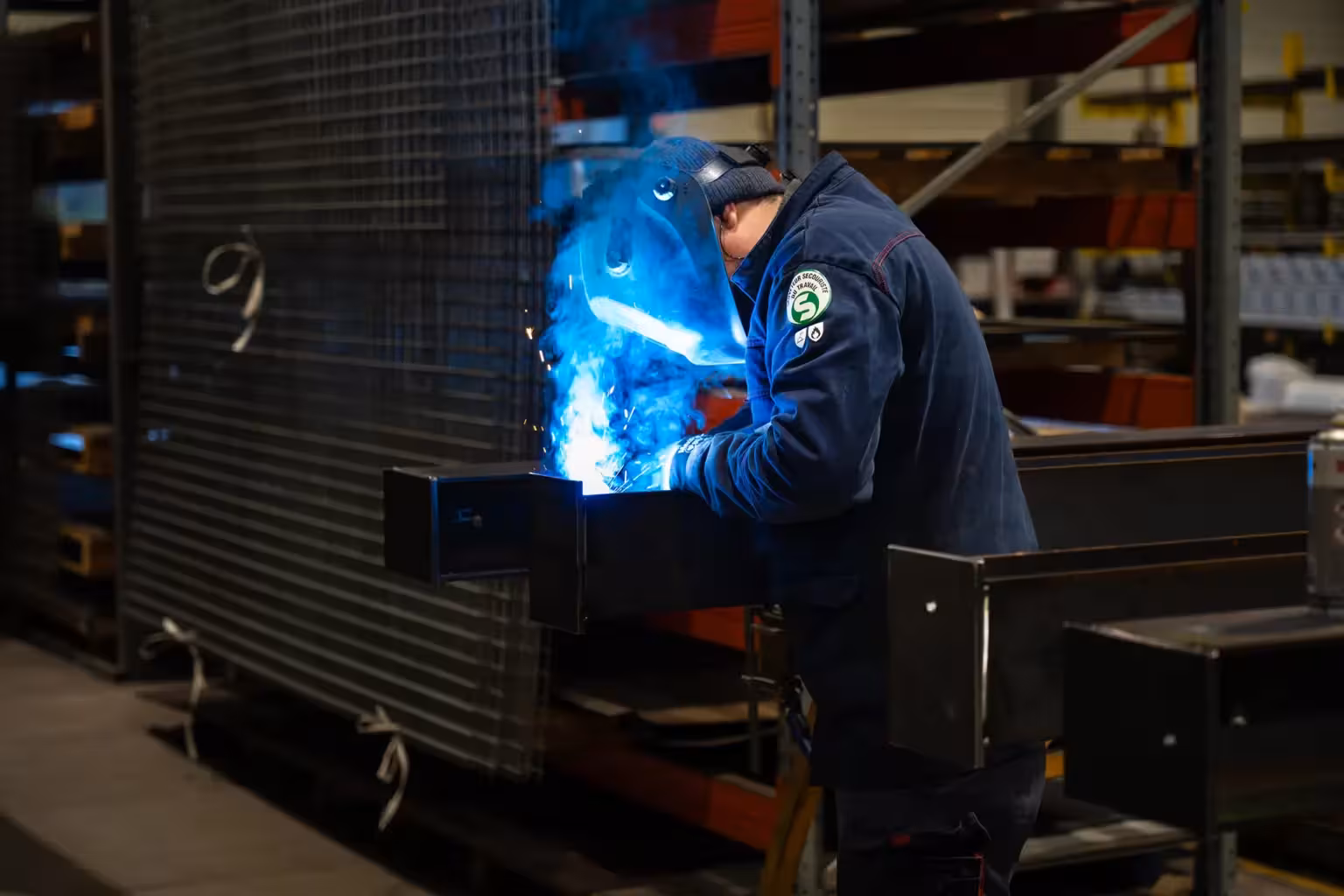 Compagnon métallier de Coyac réalisant une soudure MIG sur une pièce d'ouvrage métallique dans l'atelier de fabrication