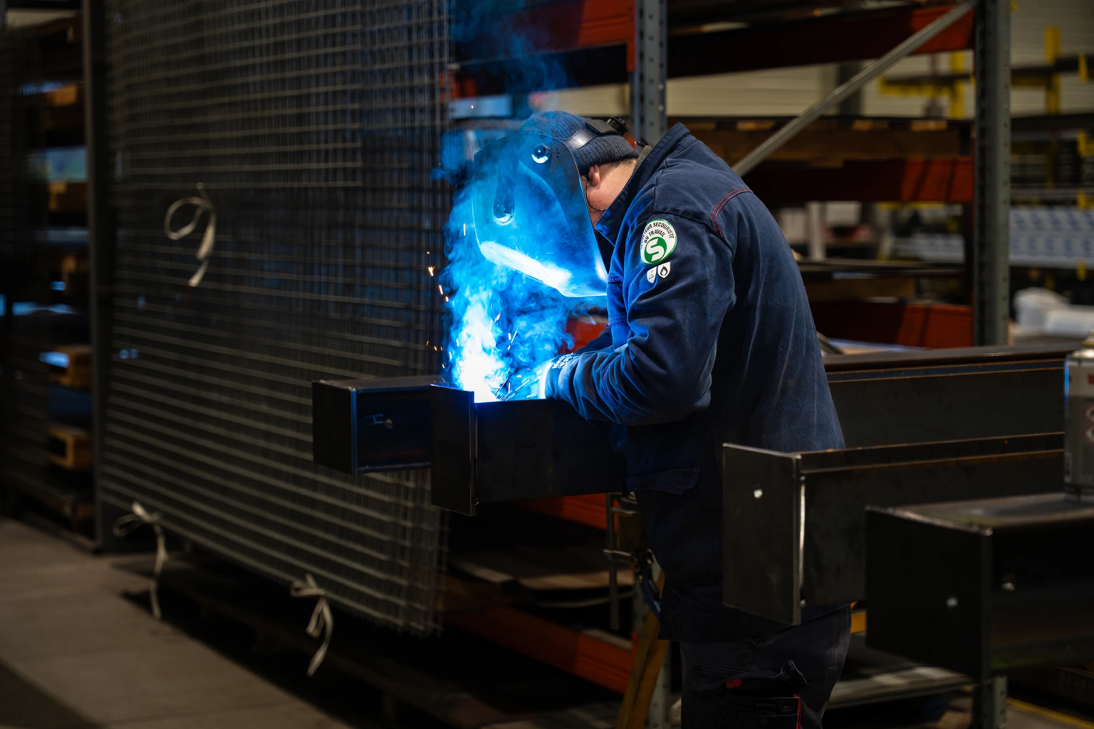Compagnon métallier de Coyac réalisant une soudure MIG sur une pièce d'ouvrage métallique dans l'atelier de fabrication